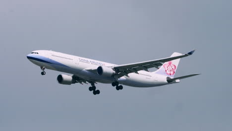 Airbus-of-China-Airlines-making-a-landing-at-Suvarnabhumi-Airport-in-Bangkok,-Thailand,-also-revealing-fluffy-clouds-and-birds-flying-by