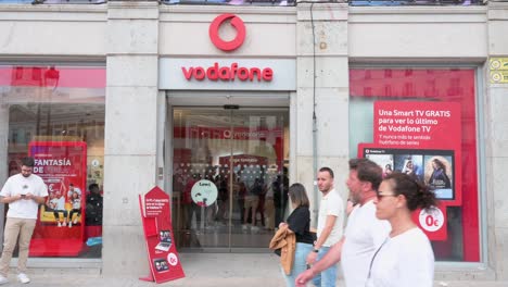 Pedestrians-and-customers-walk-past-the-British-multinational-telecommunications-corporation-and-phone-operator,-Vodafone,-store