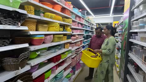 A-woman-with-her-husband-buys-a-plastic-bucket-for-collecting-things-in-a-shopping-mall