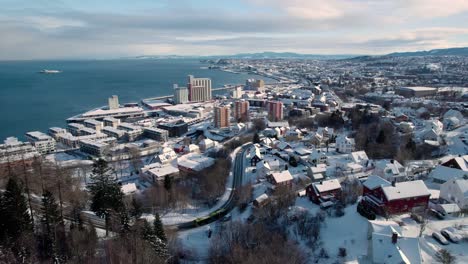 Aerial-drone-backward-moving-shot-over-a-city-in-Trondheim,-Norway-on-a-cold-winter-day