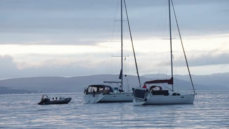 Two-small-yachts-and-a-motorised-dinghy-are-moored-not-far-from-the-coastline