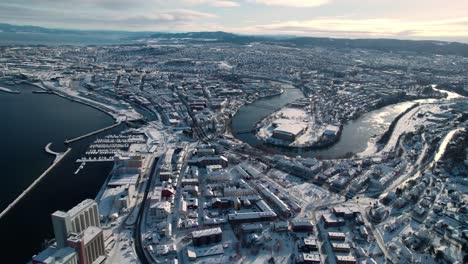 Drone-Shot-of-Trondheim,-Norway-on-Sunny-Winter-Day,-Buildings,-Harbor-and-River