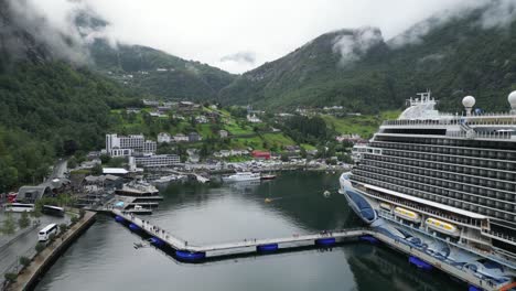 Cruise-Ship-Docked-in-Geiranger,-Norway---Tourist-People-leave-Boat-to-Visit-Village---Aerial-Circling