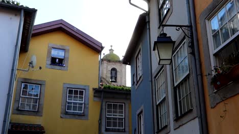 Colorful-building-walls-frame-San-Lorenzo-Dos-Riglos-Church-bell-tower-in-Largo-da-Pena-Ventosa,-Porto,-Portugal