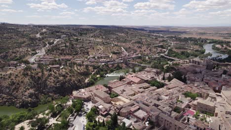 Toledo-Spanish-town-aerial-flying-above-rooftops-townscape-and-over-river-bridge