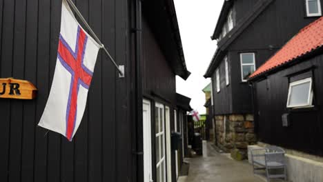 Close-up-shot-of-Faroese-flag-hanging-on-a-wooden-facade-in-Gasadalur