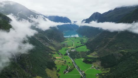 Lago-Oldevatnet-Y-Montañas-Verdes-Del-Valle-Nubes-En-Stryn,-Vestland,-Noruega---Antena