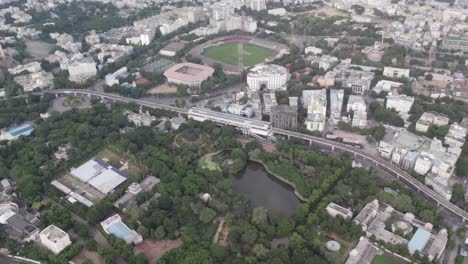 Aerial-footage-of-a-stadium-close-by,-parallel-railroad-tracks,-and-a-metro-station-in-the-middle-of-the-city