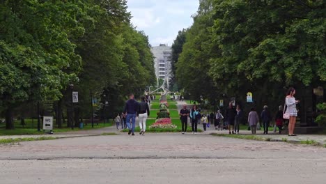 Static-shot-of-people-walking-through-the-park-in-Chorzów-in-Poland,-on-a-sunny-day,-with-a-couple-in-the-foreground