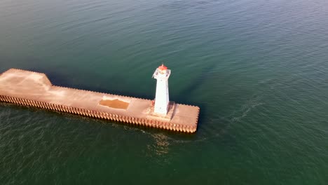 slow-moving-rotating-Drone-shot-of-the-small-light-house-at-Sodus-point-New-York-vacation-spot-at-the-tip-of-land-on-the-banks-of-Lake-Ontario