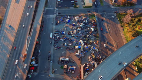 Aerial-Overhead-View-of-North-American-Homeless-Encampment-with-Cars-Driving-on-Roads-Above
