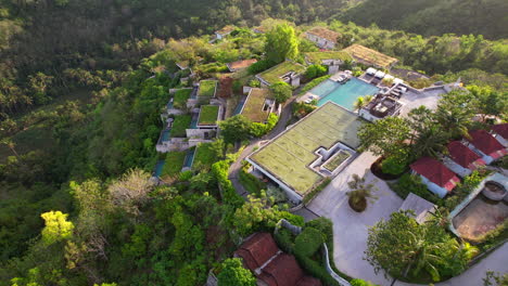 Aerial-Flying-Over-Hilltop-Estate-of-Maua-Resort-and-Hotel-in-Nusa-Penida-with-Tropical-Balinese-Nature-at-Sunrise,-Establishing-Shot
