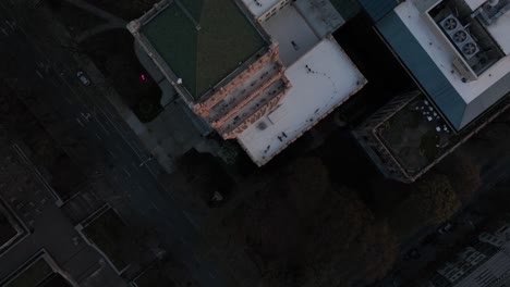 Overhead-drone-shot-flying-above-residential-buildings,-following-a-car-driving-through-the-streets-of-residential-blocks-in-the-evening,-Georgia,-USA