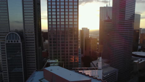 Aerial-tracking-shot-in-middle-of-buildings-in-downtown-Dallas,-sunset-in-Texas,-USA