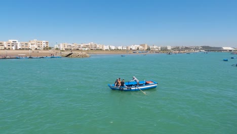 Boat-on-Bouregreg-River-with-Rabat's-distant-skyline-in-clear-daylight,-Morocco
