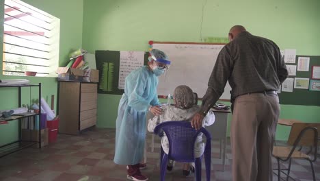 During-a-medical-brigade,-a-female-doctor-walks-and-sits-an-adult-woman-down-to-be-examined