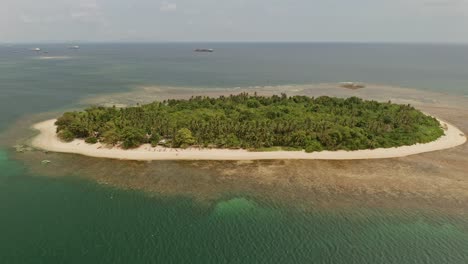 An-aerial-drone-shot-of-Alingkakajaw-Island-in-Surigao-Del-Norte,-Philippines-on-a-bright-day-surrounded-by-clear-ocean