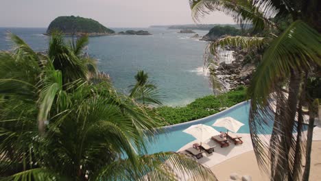 Aerial-moving-along-the-palm-trees-at-the-mesmerizing-coastline-in-Huatulco,-Mexico