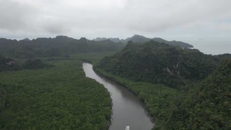 High-aerial-tracks-tourism-boat-on-humid-hazy-jungle-mountain-river