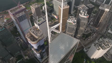 Toma-Aérea-De-Arriba-Hacia-Abajo-De-La-Torre-Lippo-Al-Lado-Del-Banco-De-China-En-La-Ciudad-De-Hong-Kong-Durante-El-Día-Soleado---Grúas-Trabajando-En-Lo-Alto-De-Edificios-Rascacielos-En-El-Centro---Vuelo-Descendente