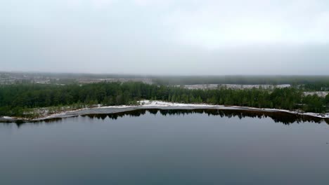 Malerische-Aussicht-Auf-Die-Wasseroberfläche,-Die-Bäume-Am-Ufer-Und-Die-Winterlandschaft-Im-Nebel