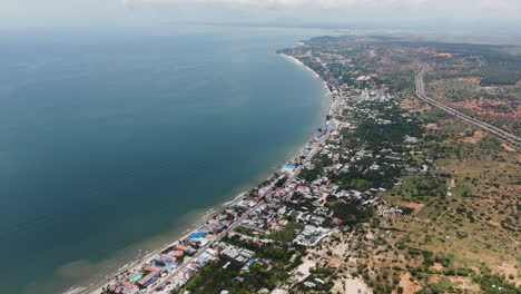 Aerial-circling-Mui-Ne-beach,-Phan-Thiet-in-distance,-Vietnam