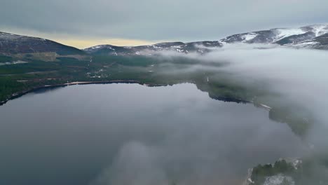 Aerial-panoramic-footage-of-mountain-lake-and-peaks-in-distance