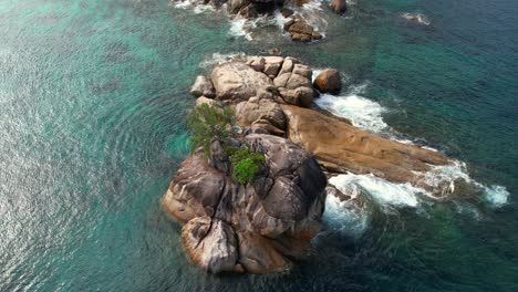 Zeitlupen-Vogelperspektive-Drohne-Schoss-über-Granitfelsen-Auf-See-Auf-Der-Insel-Mahé,-Wellen-Und-Türkisfarbenes-Wasser,-Seychellen