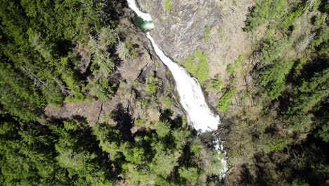 Orbiting-high-above-a-cascading-waterfall-in-a-remote-pacific-northwest-forest,-aerial