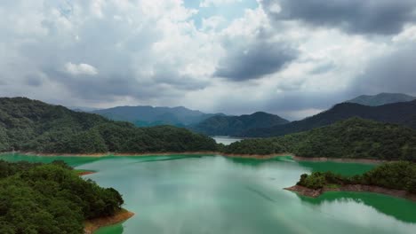 Drone-flight-over-artificial-lake-surrounded-by-green-islands-during-cloudy-day-in-Taiwan,-Asia