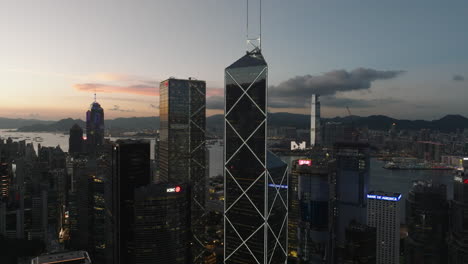 Aerial-approaching-shot-of-Bank-of-China-and-IFC-Tower-during-golden-sunset-in-Hong-Kong-City-at-dusk