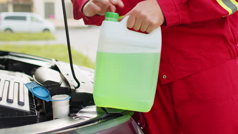 Service-worker-man-pours-car-fluid-windscreen-green-cleaning-washer-glass-summer-or-winter-cleaner