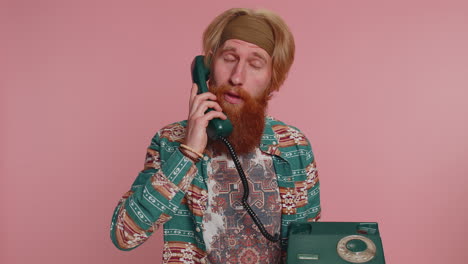 Hippie-redhead-man-talking-on-wired-vintage-telephone-of-80s,-says-hey-you-call-me-back-conversation