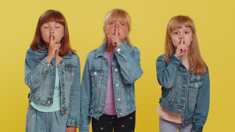Three-girls-siblings-friends-presses-finger-to-lips-makes-silence-gesture-sign-do-not-tells-secret