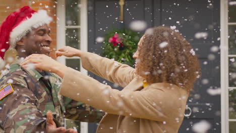 Couple-with-American-army-husband-wearing-Santa-hat-home-on-leave-hugging-outside-house-at-Christmas-in-snow---shot-in-slow-motion