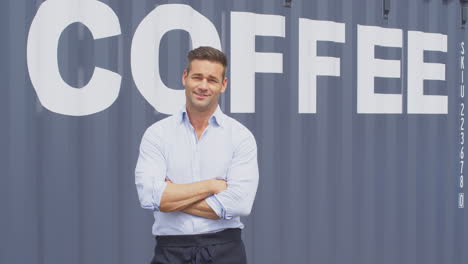 Portrait-Of-Male-Owner-Of-Coffee-Shop-Or-Distribution-Business-Standing-By-Shipping-Container