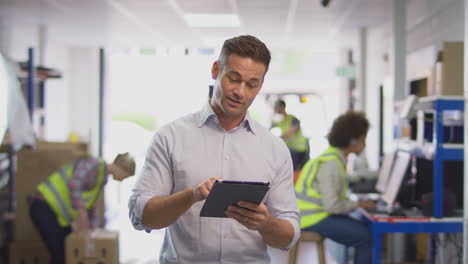 Male-Manager-In-Busy-Logistics-Distribution-Warehouse-Using-Digital-Tablet