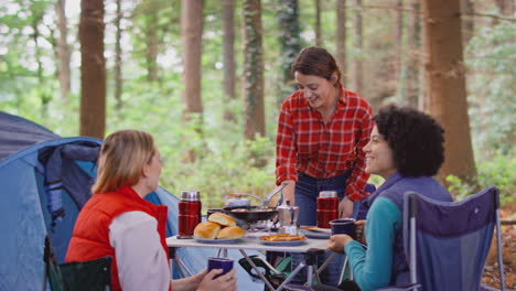 Grupo-De-Amigas-De-Vacaciones-En-Camping-En-El-Bosque-Cocinando-Comida-Sentada-Junto-A-Una-Tienda-De-Campaña