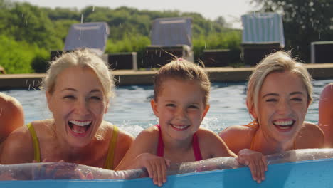Lächelnde-Mehrgenerationenfamilie-Im-Sommerurlaub,-Die-Sich-Im-Schwimmbad-Auf-Der-Luftmatratze-Entspannt