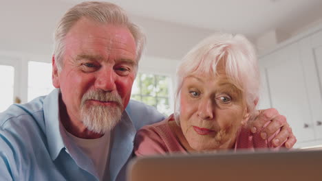 Älteres-Ehepaar-Im-Ruhestand-In-Der-Küche-Zu-Hause-Und-Macht-Videoanrufe-Mit-Laptop