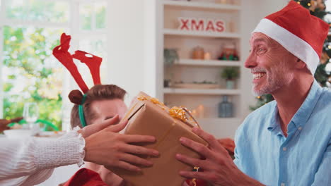 Mehrgenerationenfamilien-Feiern-Weihnachten-Zu-Hause-Mit-Weihnachtsmützen-Und-Geweihen-Und-öffnen-Geschenke