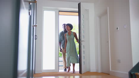 Romantic-Couple-With-Man-Carrying-Woman-Over-Threshold-Into-Hallway-Of-New-Home