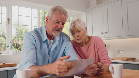 Besorgtes-Rentnerehepaar-Schaut-Zu-Hause-Auf-Rechnungen-Und-Ist-Besorgt-über-Die-Lebenshaltungskosten