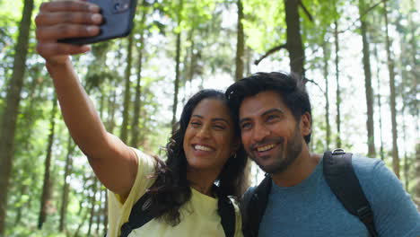 Paar-Macht-Selfie-Mit-Dem-Handy-Beim-Wandern-Oder-Spazierengehen-Durch-Die-Sommerliche-Waldlandschaft
