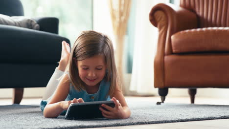 Junges-Mädchen-Sitzt-Zu-Hause-Auf-Dem-Boden-Der-Lounge-Und-Spielt-Ein-Spiel-Oder-Schaut-Sich-Einen-Film-Auf-Einem-Digitalen-Tablet-An