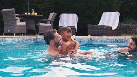 Same-Sex-Family-With-Two-Dads-And-Son-On-Holiday-In-Swimming-Pool-Together
