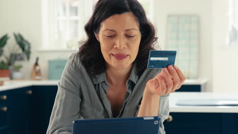 Close-Up-Of-Mature-Woman-With-Credit-Card-Using-Digital-Tablet-At-Home-To-Book-Holiday-Or-Shop
