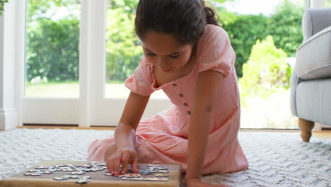 Girl-At-Home-Sitting-On-Floor-In-Lounge-Doing-Jigsaw-Puzzle