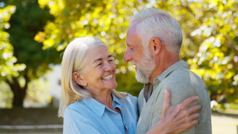 Portrait-Of-Loving-Senior-Couple-Standing-And-Hugging-Outdoors-In-Garden-Park-Or-Countryside