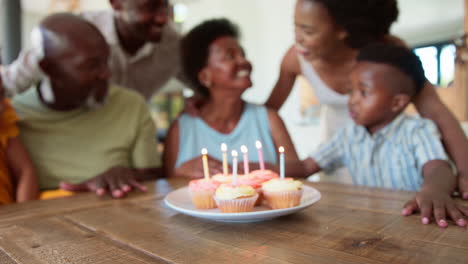 Multi-Generation-Family-Celebrate-Grandmother's-Birthday-With-Cake-And-Candles-Around-Table-At-Home